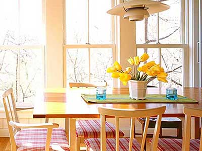 Dining room with Marvin windows behind the table and chairs, letting in the bright sunlight