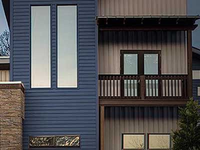 Modern, uniquely shaped home with blue and light brown Rollex siding