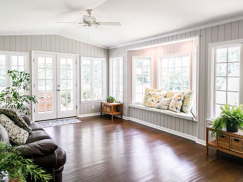 Modern living room space with large white windows all around letting the sunlight in